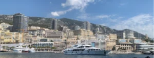 Bateau amarré dans le port de Monaco, avec des yachts de luxe et la vue sur les montagnes